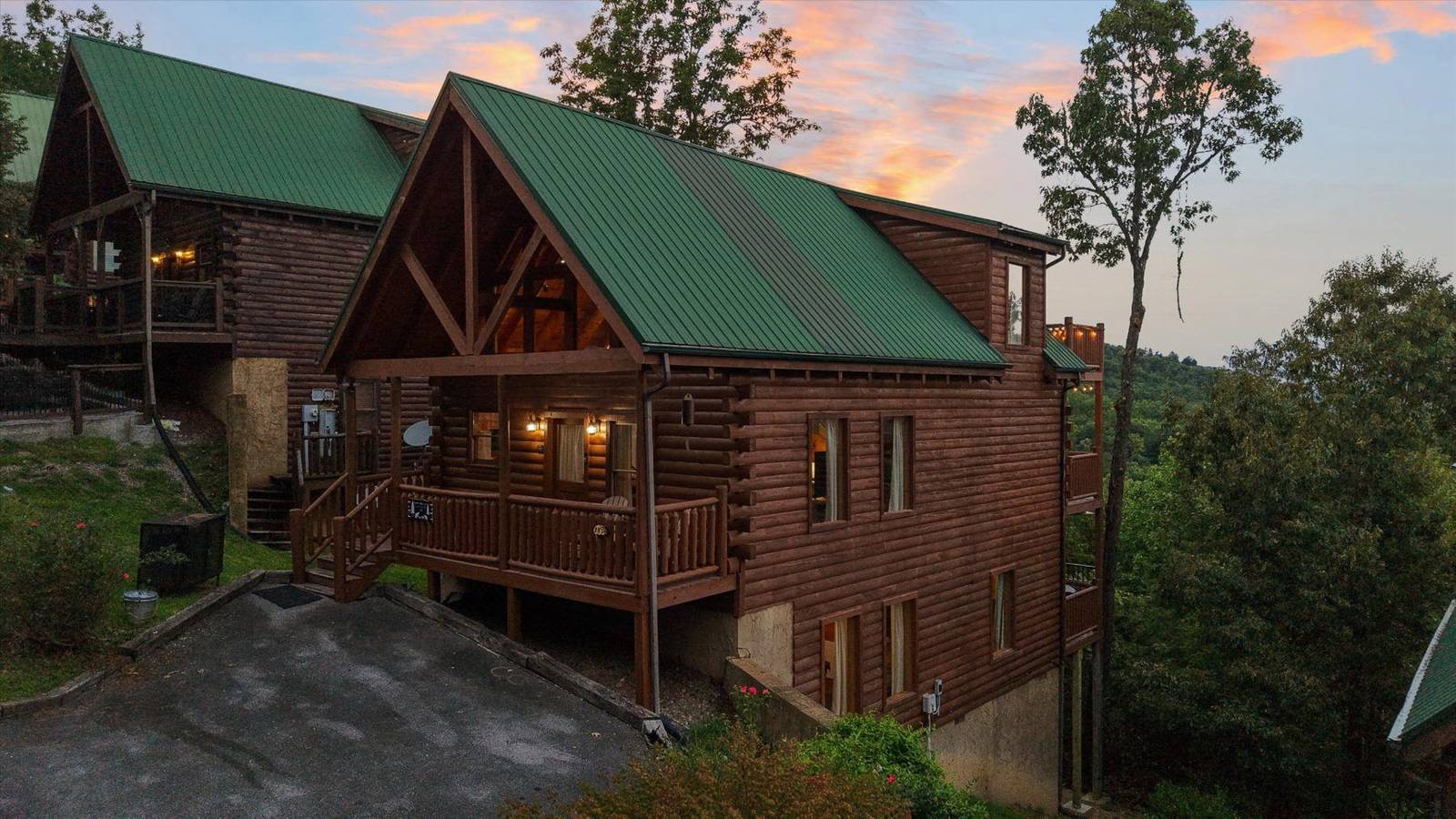 Two log cabins with green roofs and balconies against a sunset sky