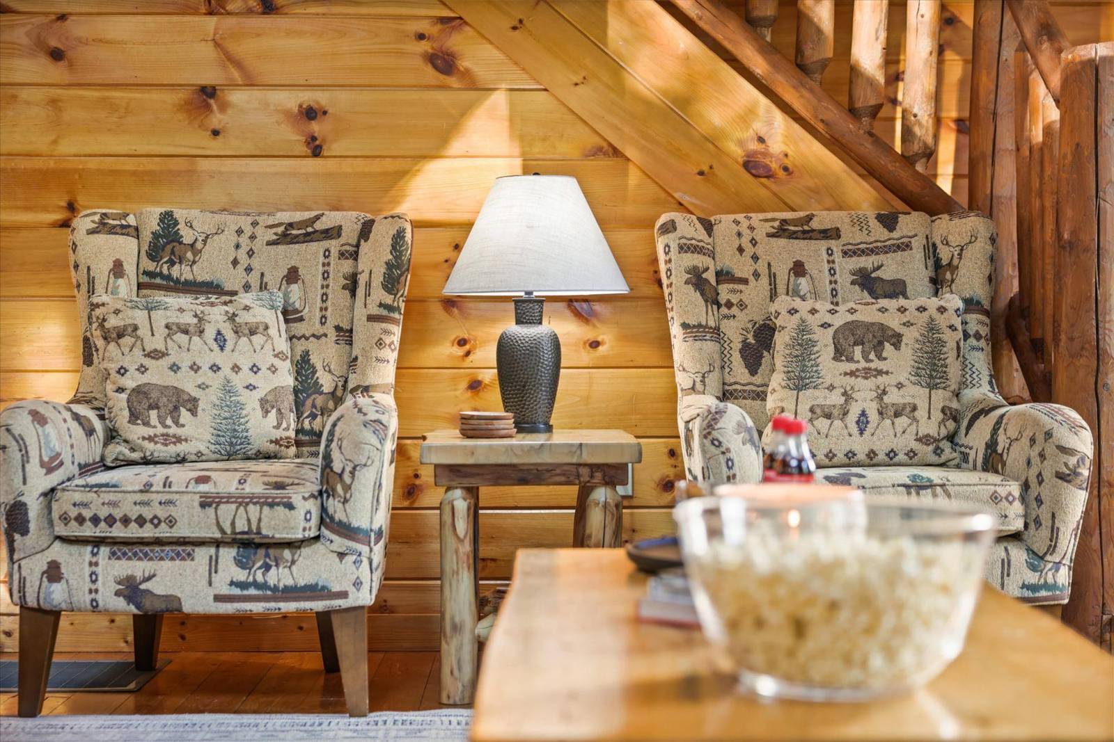 Two rustic upholstered armchairs, wooden table, and lamp