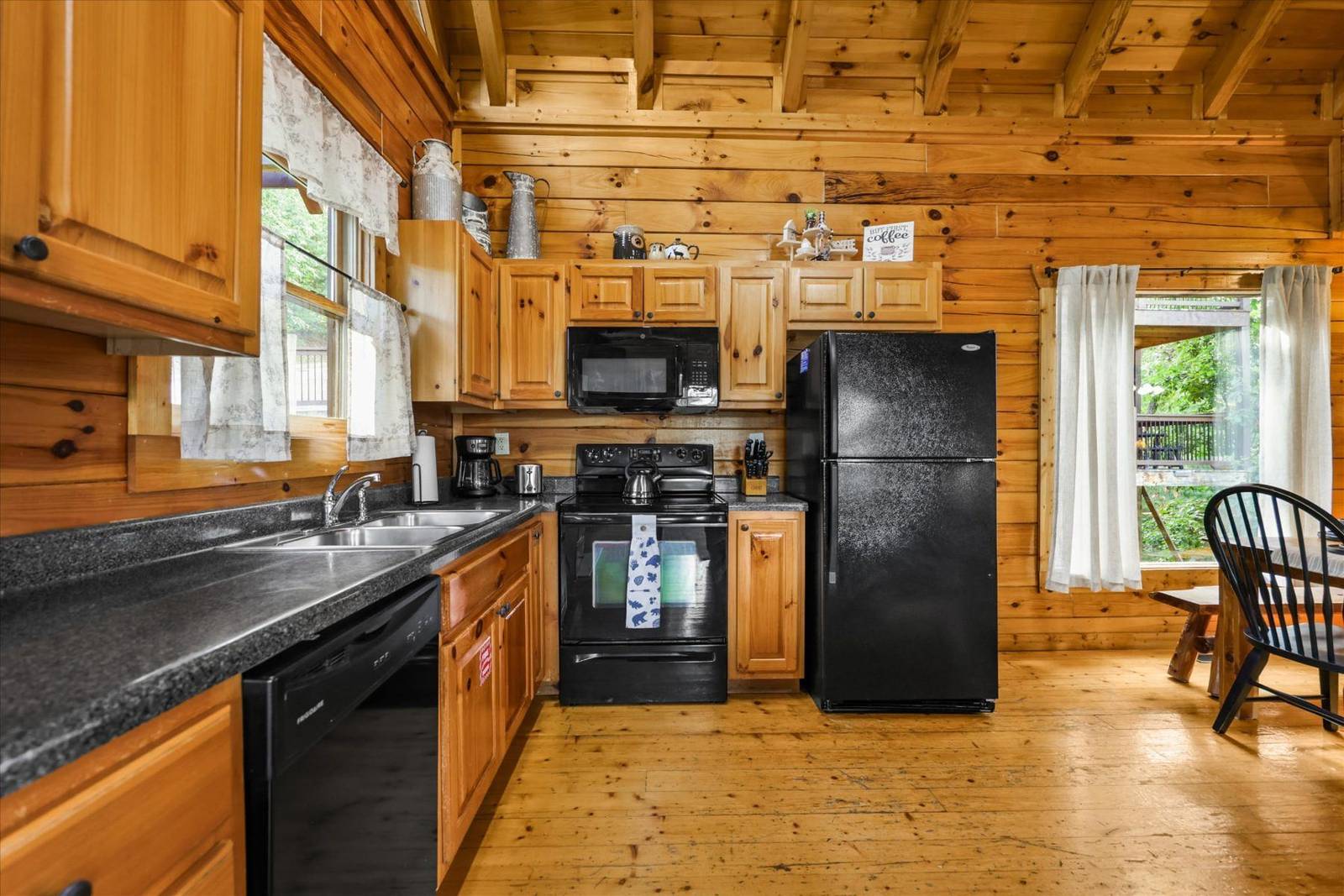 Wooden kitchen with black appliances, wooden cabinets, and window
