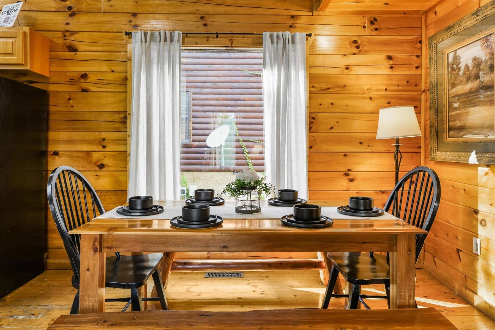 Wooden dining table set with black dishes and chairs in a cabin