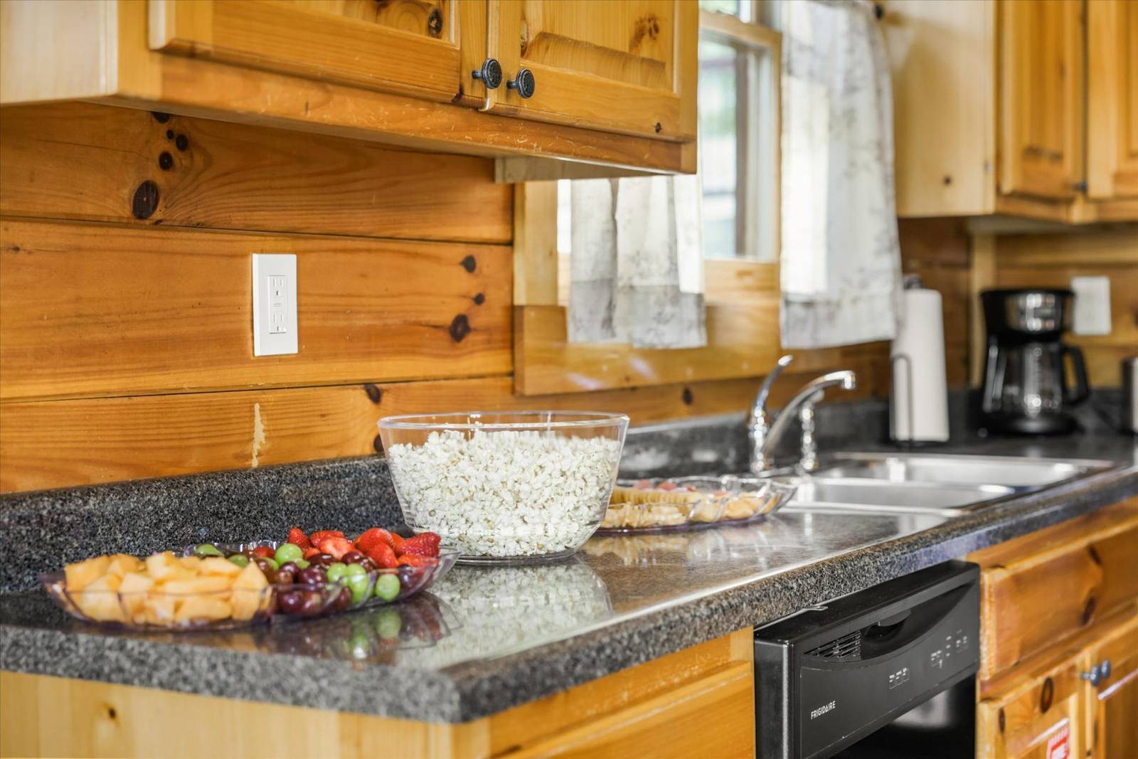Wooden kitchen counter with fruit bowls, sink, and dishwasher