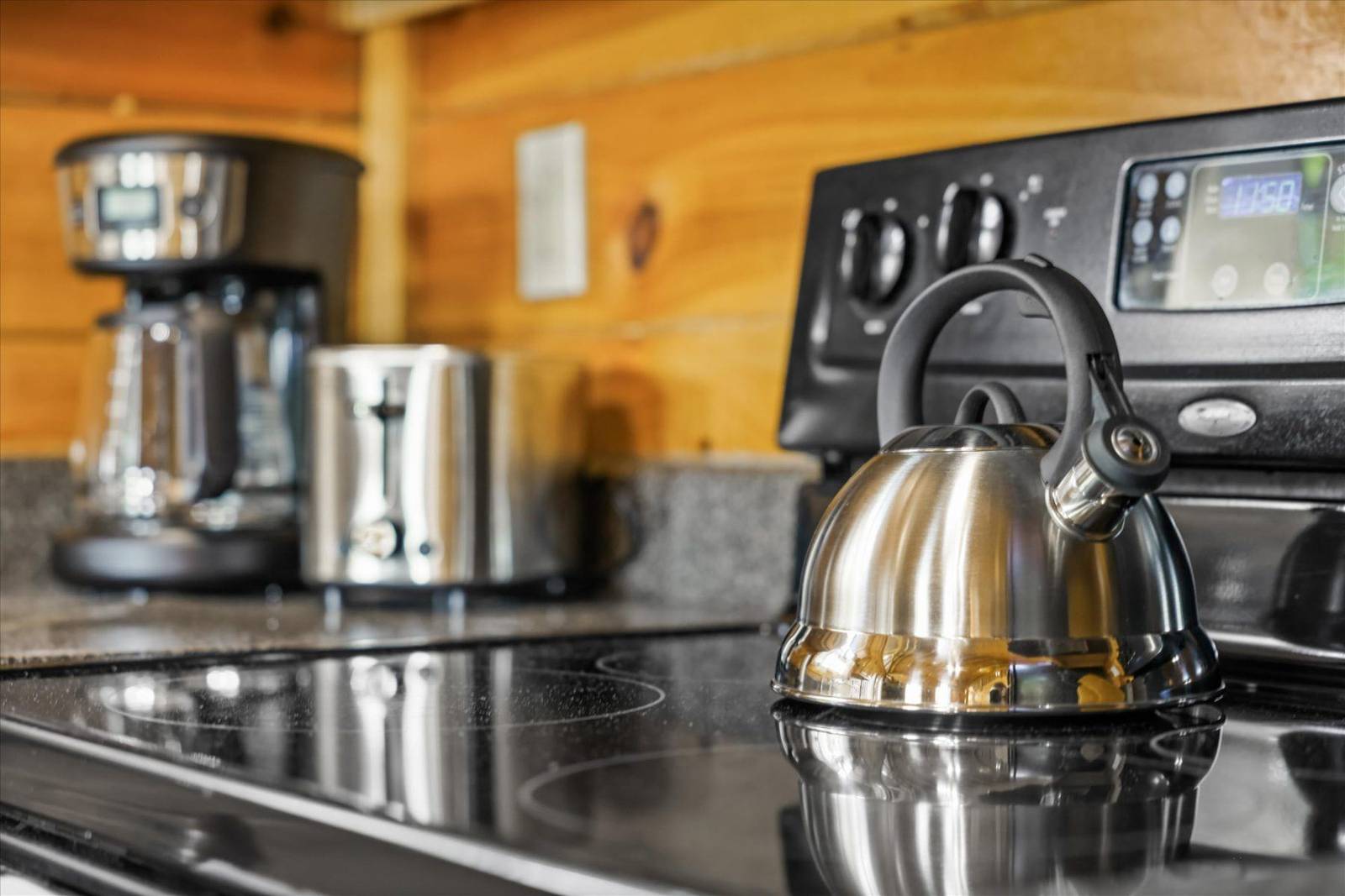 Stainless steel kettle on stovetop, with coffee maker and toaster in background