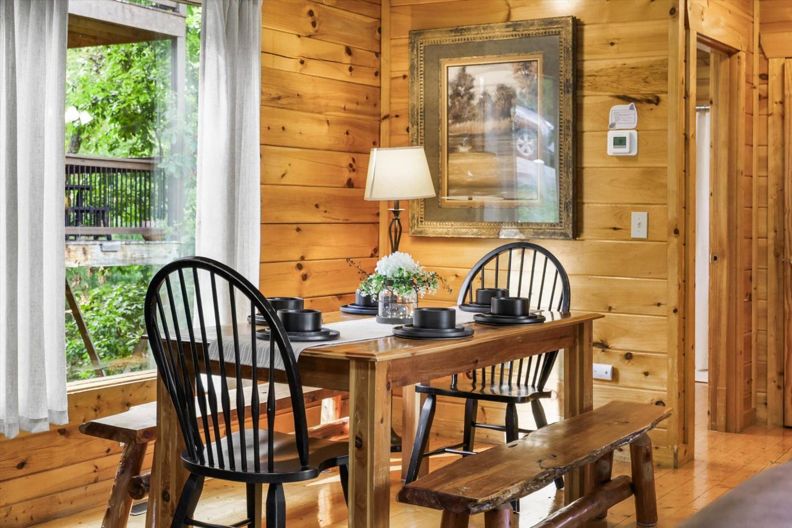 Wooden dining table set with chairs, bench, and forest view