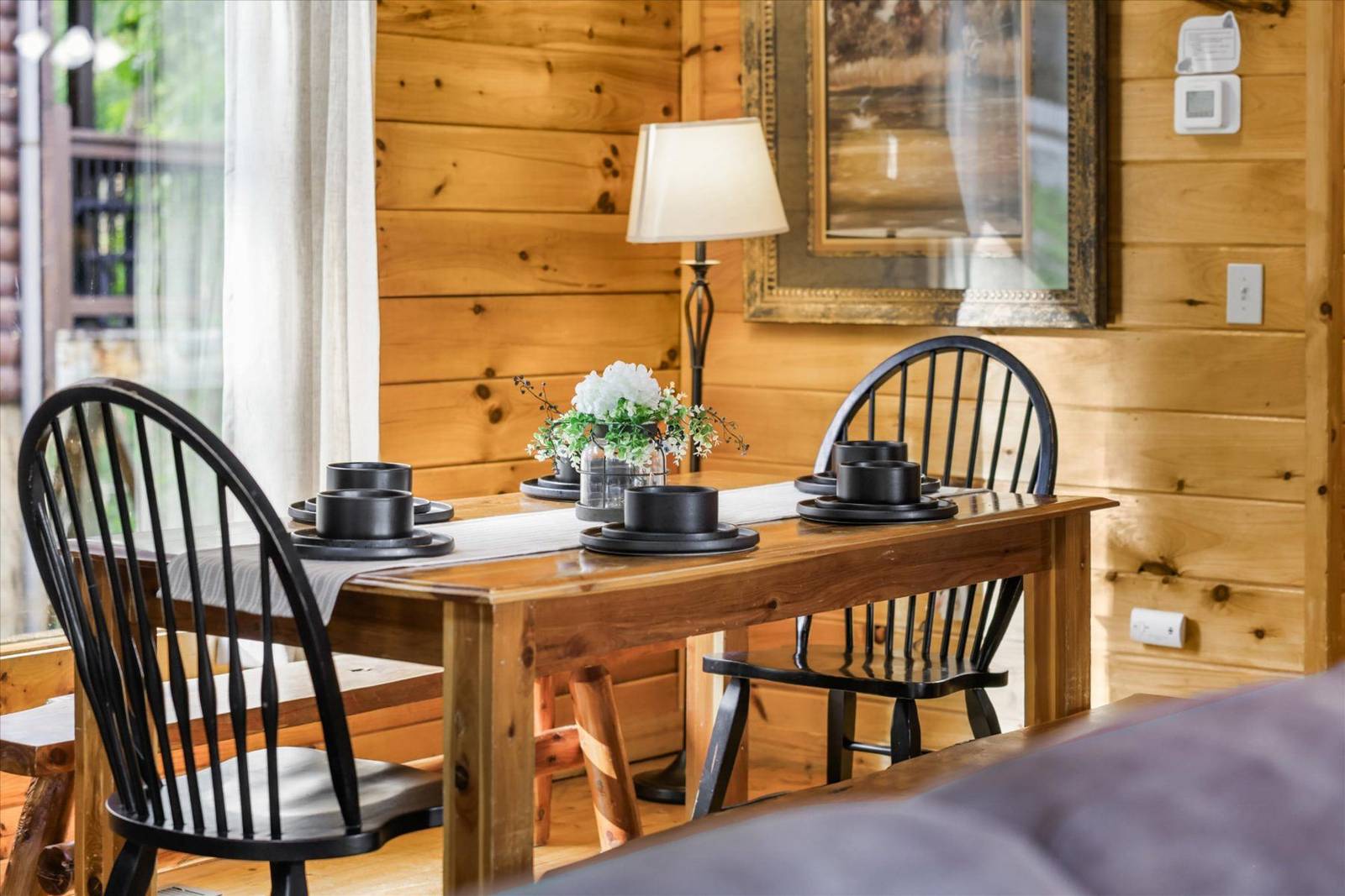Wooden dining table set with black dishes, chairs, and white flowers
