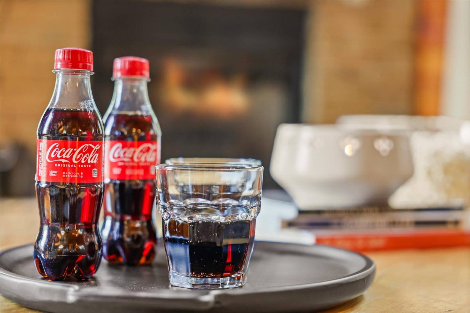 Two Coca-Cola bottles and a glass of soda on a tray