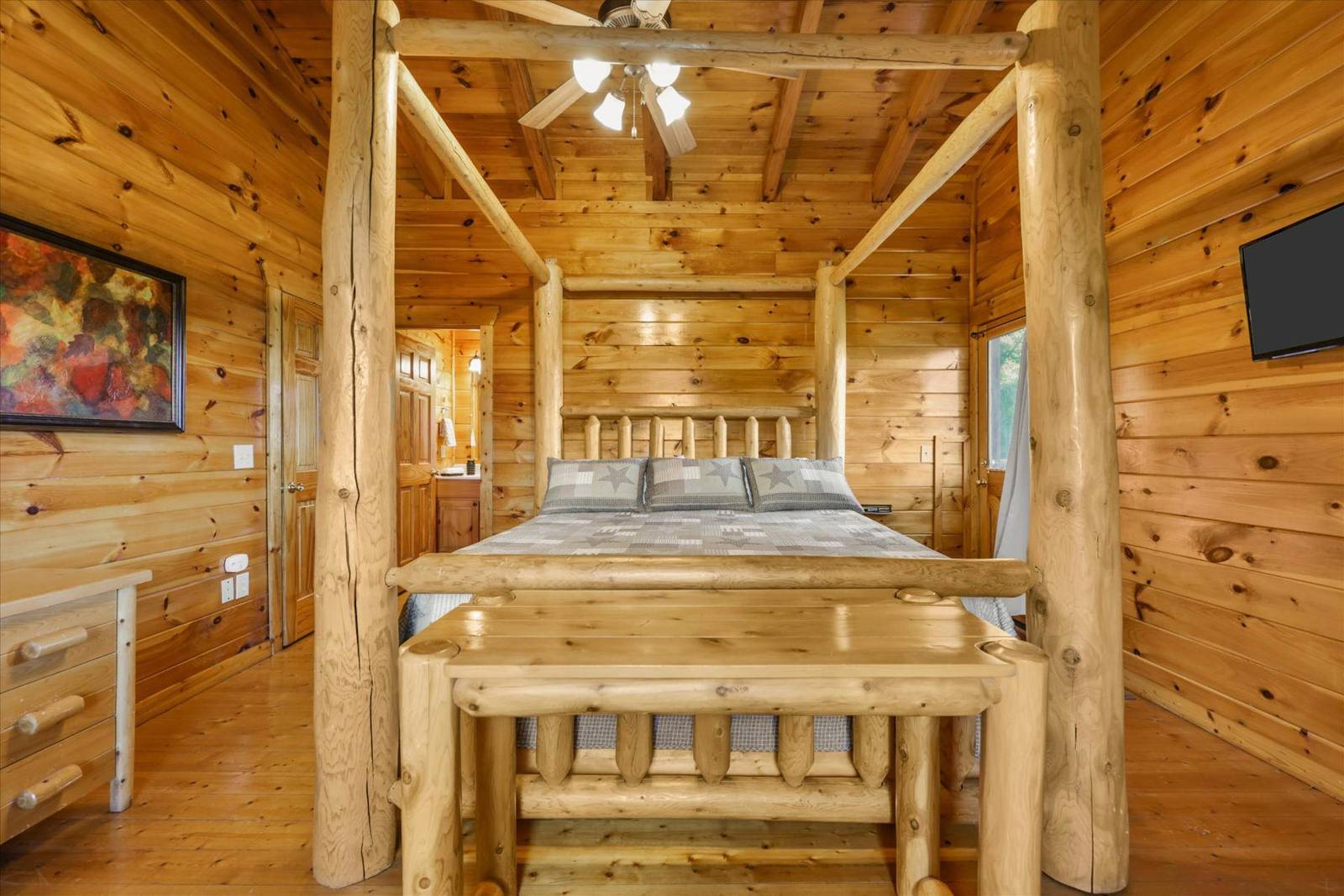 Log cabin bedroom with log four-poster bed and ceiling fan