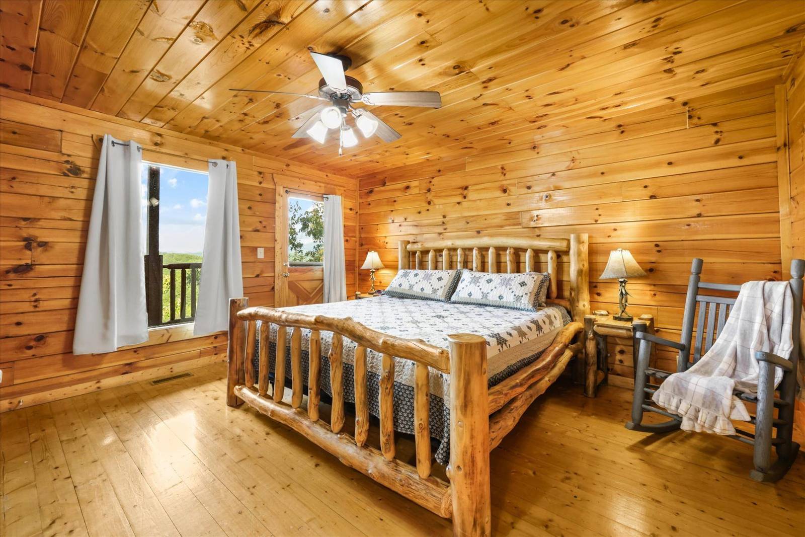 Rustic bedroom with log bed, rocking chair, and wood paneled walls