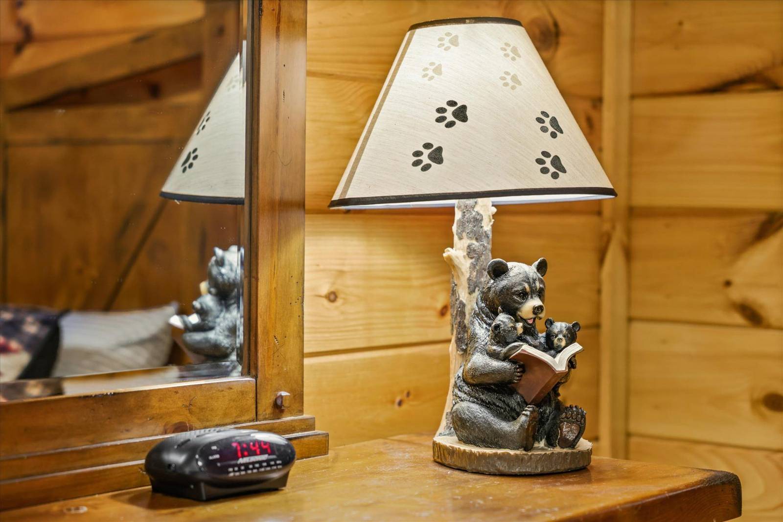 Table lamp with bear family base and paw print shade next to an alarm clock