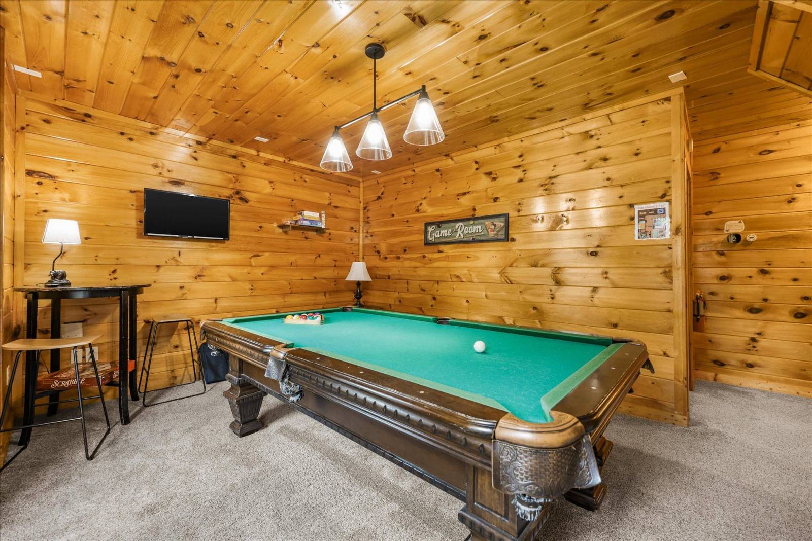 Game room with wood walls, pool table, television, and small tables
