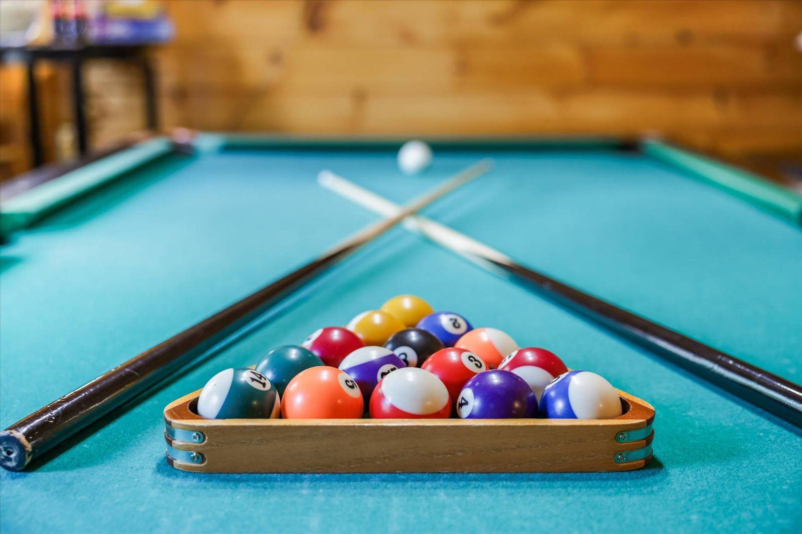 Racked pool balls and cues on a blue billiard table