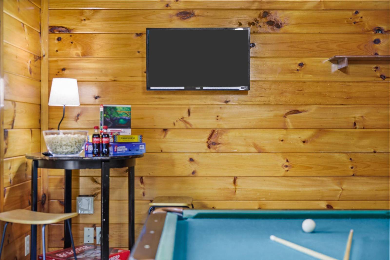 Mounted TV and table with snacks next to a pool table