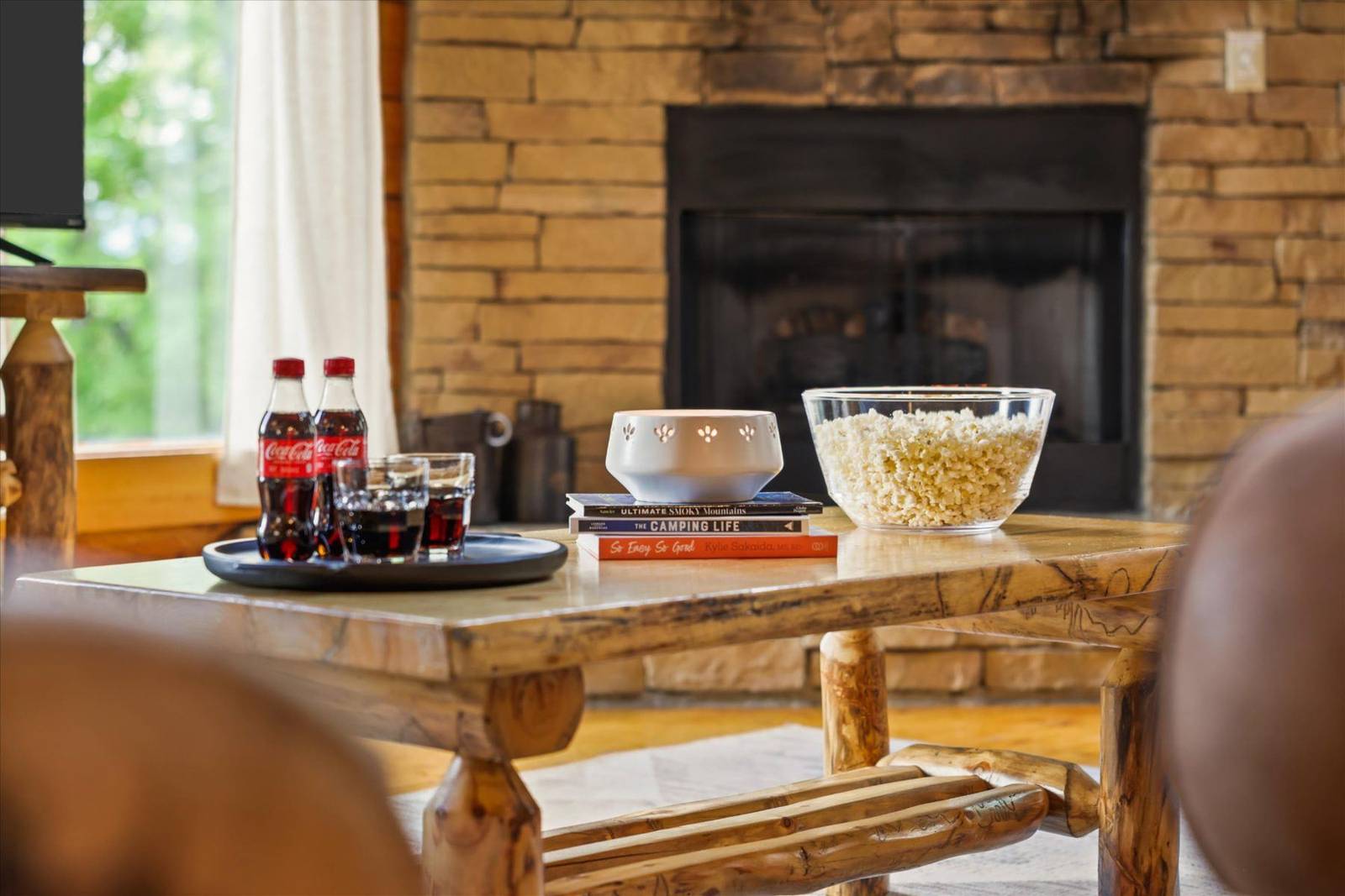 Coffee table with popcorn, soda, glasses, decorative bowl, and books