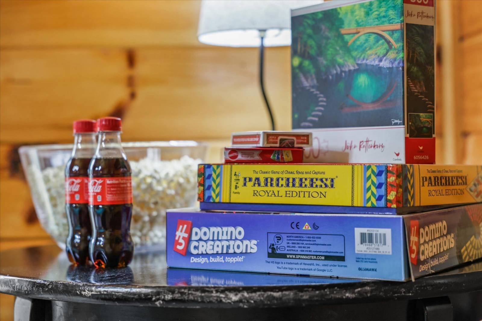 Two Coca-Cola bottles, popcorn, stacked board games, and a puzzle box