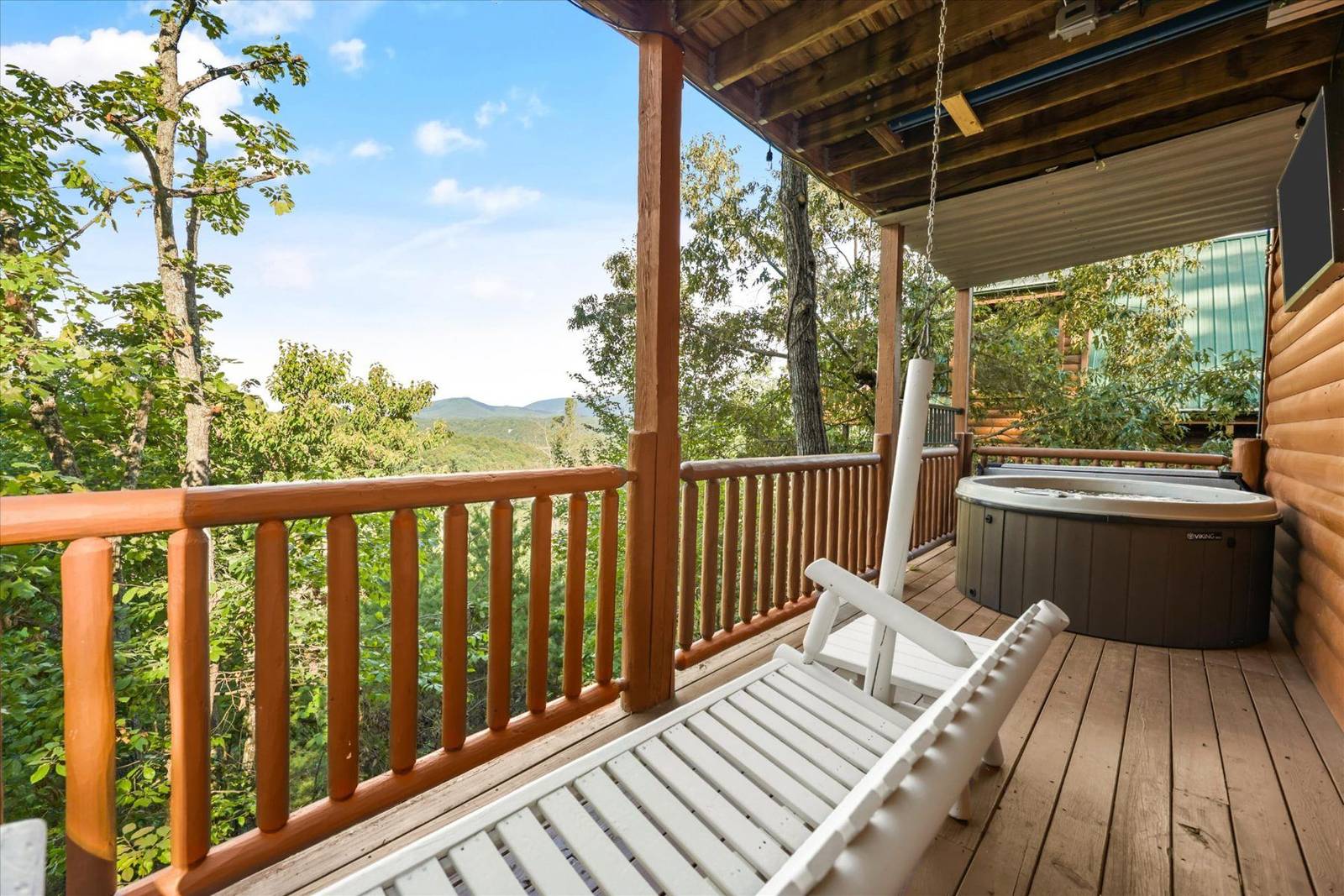 Wooden deck with hot tub, white lounge chair, and mountain view