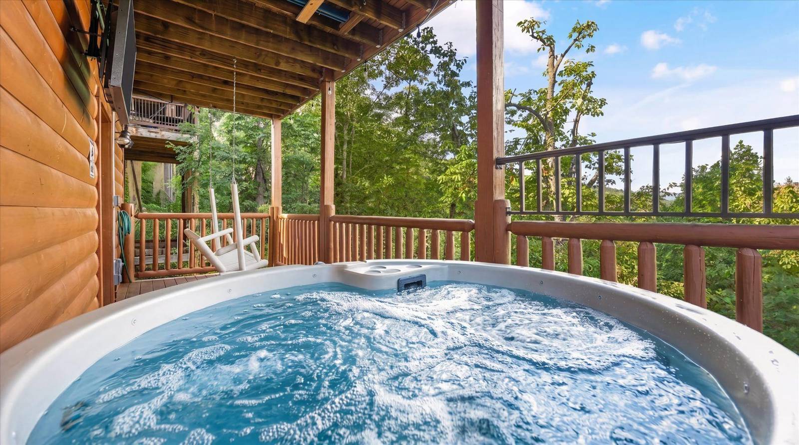 Bubbling hot tub on a wooden deck with a forest view