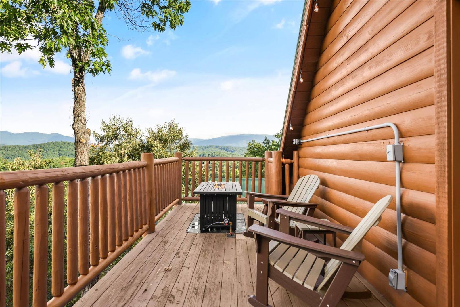 Wooden deck with chairs, fire pit table, and mountain-lake view