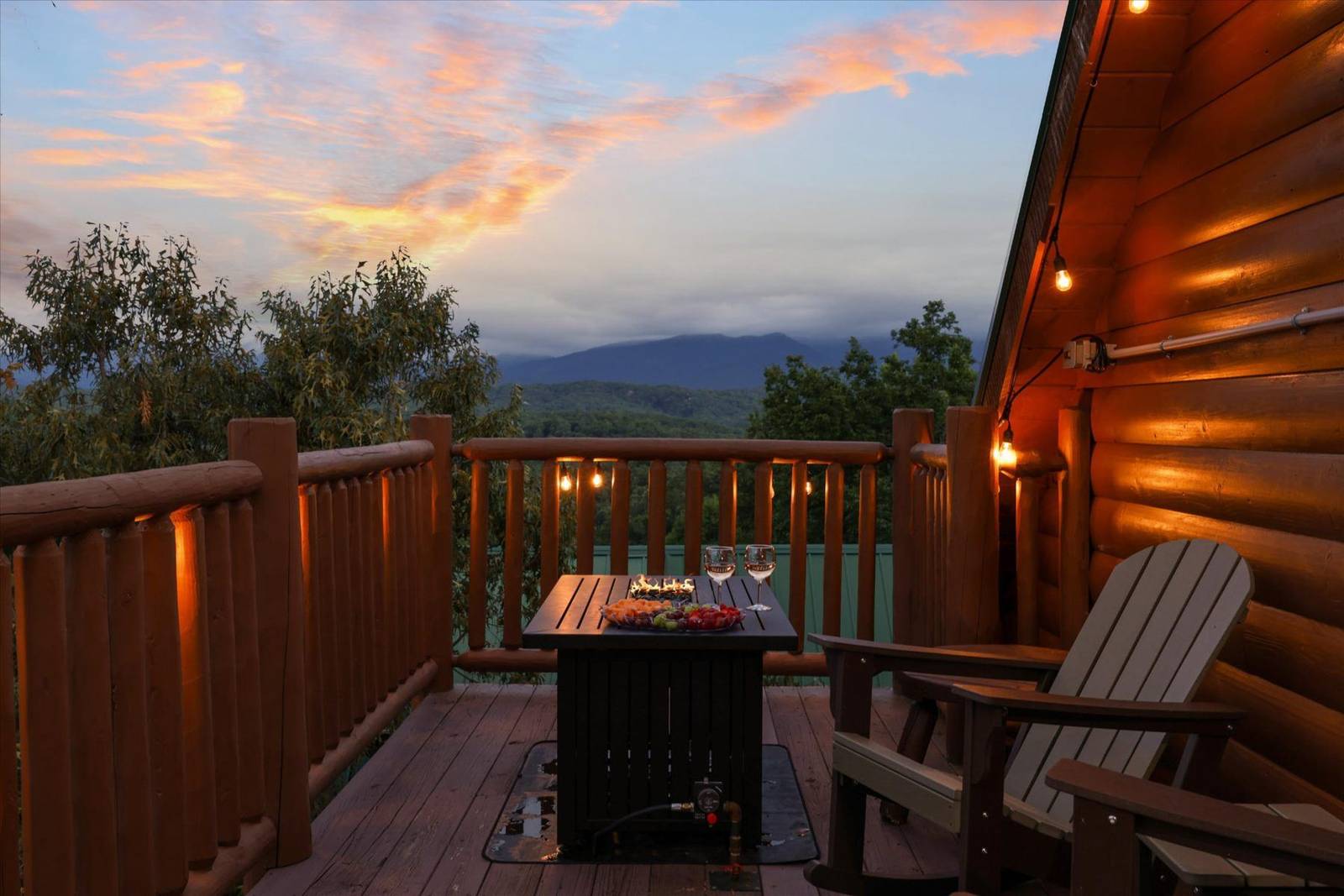 Wooden deck with fire table, chairs, string lights, and mountain view